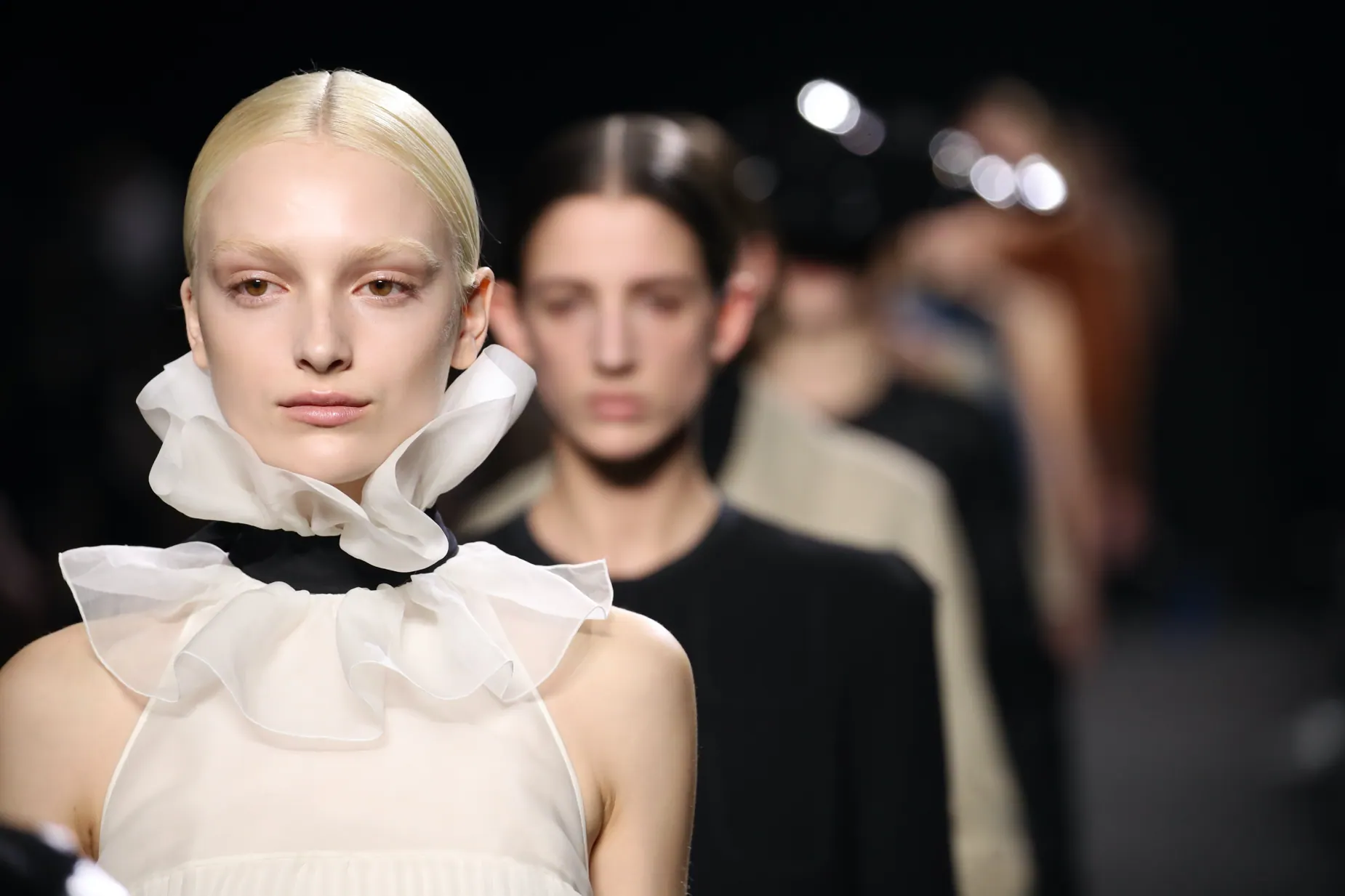 Close-up runway portrait in an oversized white ruffled collar