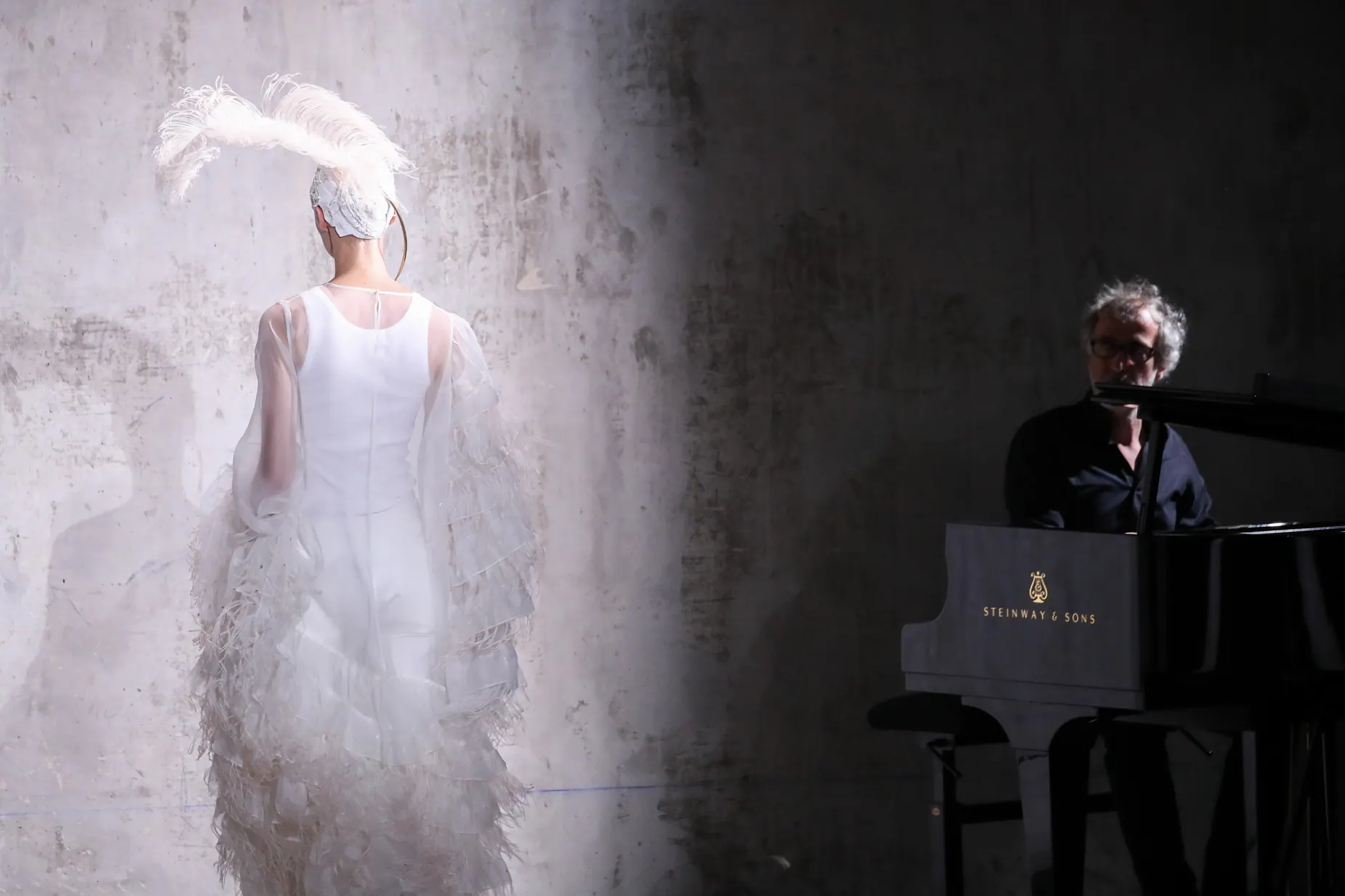 Ethereal white fashion silhouette beside pianist at Dries Van Noten presentation