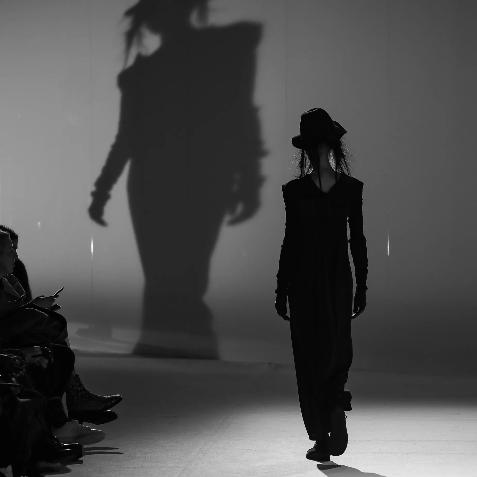 Yohji Yamamoto model walking beneath an oversized shadow